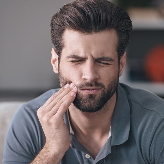 Man in need of emergency dentistry holding cheek