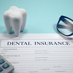 Dental insurance form, calculator, glasses, and molar