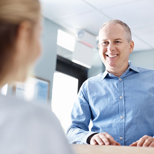 Man handing in dental insurance forms at dental office front desk