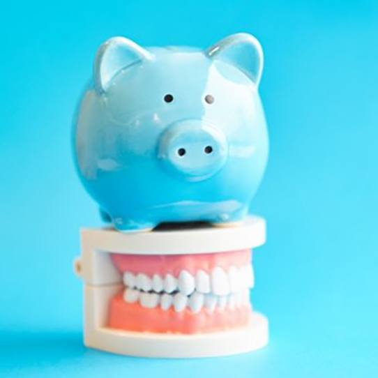 light blue piggy bank sitting on top of set of full dentures