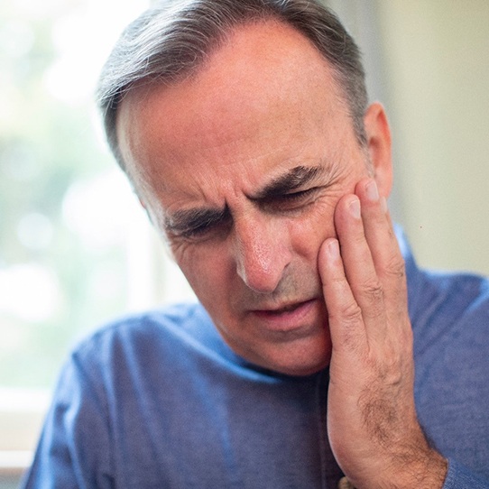 Older man with toothache rubbing cheek