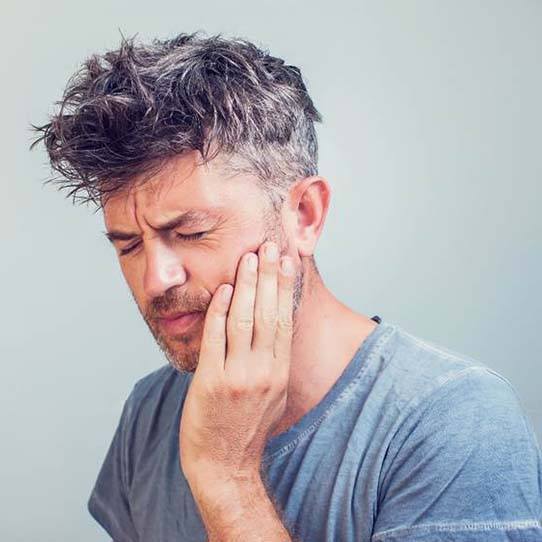 Man with a dental emergency holding his cheek