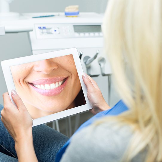 Woman looking at virtual smile design on computer screen