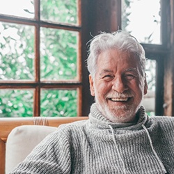 an older man smiling while sitting on a chair