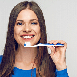 a patient holding her toothbrush and smiling in Shelton