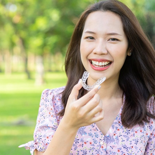 Smiling woman outside holding Invisalign