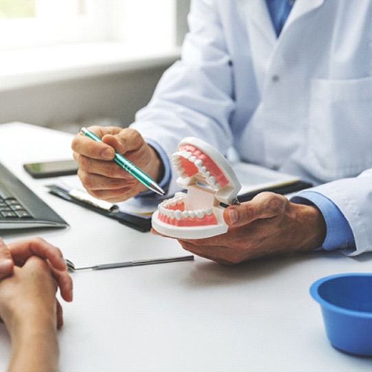 A dentist holding a mouth mold and discussing clear braces with a prospective patient