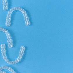 Clear aligners arranged against blue background