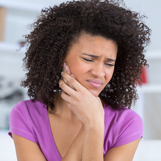 Woman in need of tooth extraction holding jaw